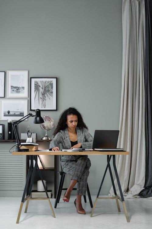 Woman using a laptop at a desk, reviewing financial documents and planning capital investments with tax consultancy support.