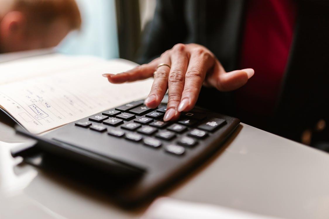 A photo showing a person using a calculator at a desk.