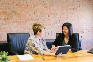 Two women looking at a tablet and talking